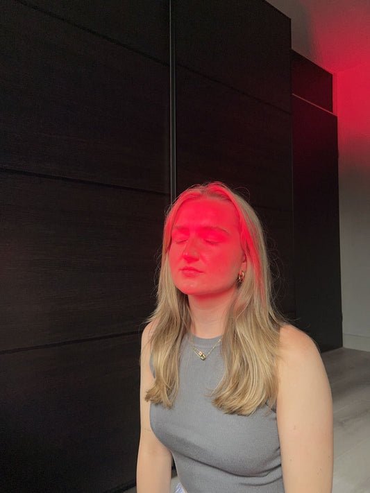 Vrouw onder roodlichttherapie met rood licht op het gezicht