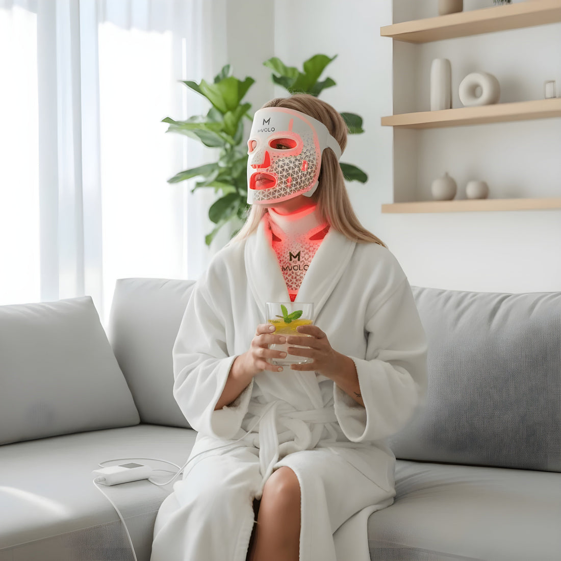 Vrouw draagt een LED-gezichtsmasker thuis terwijl ze ontspant op de bank